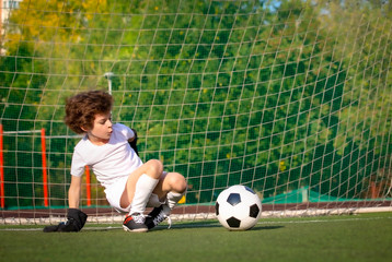 Summer soccer tournament for young kids. football club. emotions and joy of the game. Young goalie. Kids - soccer champion. Boy goalkeeper in football sportswear on stadium with ball. Sport concept.