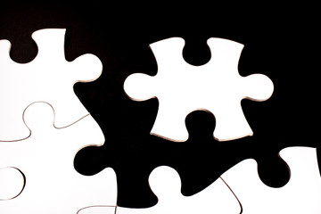 Unfinished white jigsaw puzzle pieces on black background