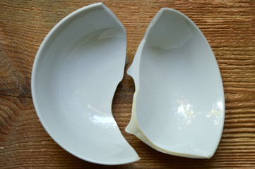 Broken white ceramic bowl on wooden background