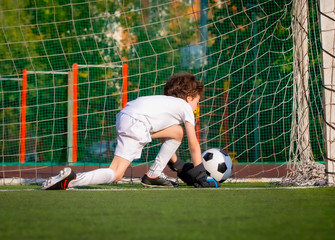 Summer soccer tournament for young kids. football club. emotions and joy of the game. Young goalie. Kids - soccer champion. Boy goalkeeper in football sportswear on stadium with ball. Sport concept.