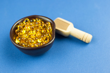Fish oil capsules on blue background, vitamin D supplement
