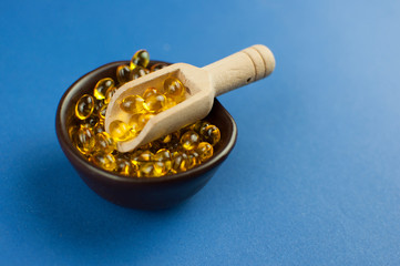 Fish oil capsules on blue background, vitamin D supplement