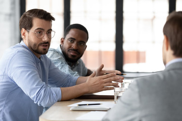 Focused businessman sit at desk in office discuss cooperation with potential client or partner,...