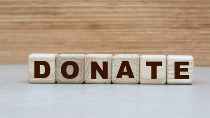 Naklejka premium concept of the word DONATE on cubes on a wooden background