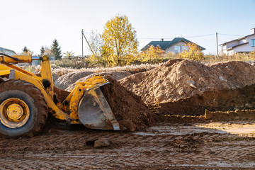large yellow wheel loader aligns a piece of land for a new building. Preparation of the land for...