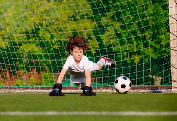 Summer soccer tournament for young kids. football club. emotions and joy of the game. Young goalie. Kids - soccer champion. Boy goalkeeper in football sportswear on stadium with ball. Sport concept.