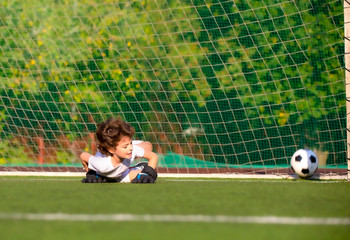 junior soccer goalkeeper. Disappointed boy in white goalie sportswear. Goalkeeper missed a goal...