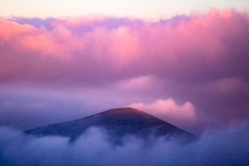 View of volcano peak covered with pink clouds