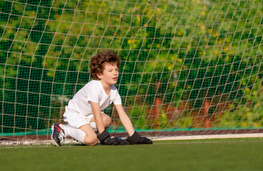 Summer soccer tournament for young kids. football club. emotions and joy of the game. Young goalie. Kids - soccer champion. Boy goalkeeper in football sportswear on stadium with ball. Sport concept.