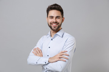 Smiling successful young unshaven business man in light shirt posing isolated on grey background...