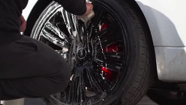 Car valet cleaning luxury black allow wheels on car with soapy sponge