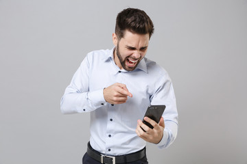 Angry young unshaven business man in light shirt isolated on grey background. Achievement career...