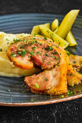 Close up view of baked bacon with mashed potato and pickle cucumber