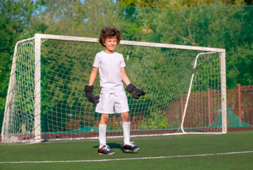 Summer soccer tournament for young kids. football club. emotions and joy of the game. Young goalie. Kids - soccer champion. Boy goalkeeper in football sportswear on stadium with ball. Sport concept.