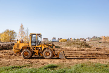 large yellow wheel loader aligns a piece of land for a new building. Preparation of the land for the auction. Leveling the landscape and adding sand for construction.