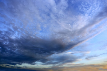 Burzowe chmury na błękitnym niebie w czasie zachodu słońca. 

