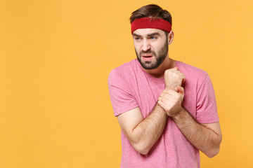 Dissatisfied young bearded fitness sporty guy sportsman in headband t-shirt spend weekend in home...