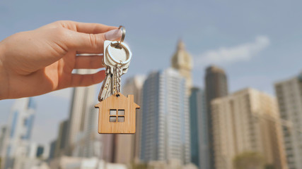 Real estate purchase concept. The girl holds the keys to a new house on the background of a Dubai...