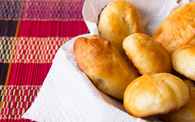 Bakery background. Homemade bakery. Patties in a basket on a white napkin.Traditional Russian pies (pirozhki). Russian cuisine. Pies with apple, closeup. Sweet dessert.