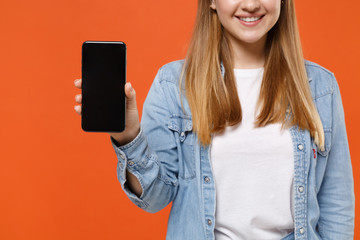 Cropped image of smiling young woman girl in casual denim clothes posing isolated on orange...