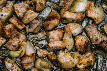 Cooking meat in a pan. Meat, onions and spices are grilled. Pieces of meat close-up. Top view, flat lay.