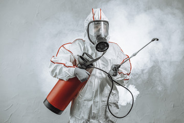 portrait of professional full armed disinfector against COVID 10, using sprays for removing bacterias from surface. wearing protective mask, gloves and suit. pandemic, epidemic, coronavirus concept