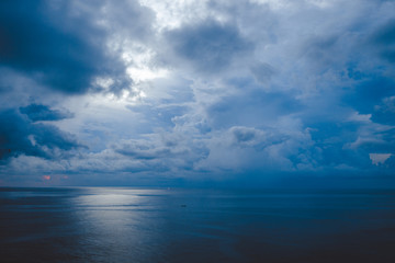 Obraz premium Beautiful blue sunset on the ocean with big waves and cliffs and cliffs. Bali island with its tropical and exotic nature. Sunrise over the sea and ocean. Phantom blue in sunset