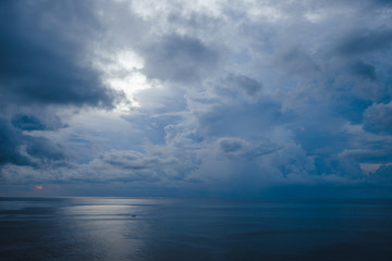 Beautiful blue sunset on the ocean with big waves and cliffs and cliffs. Bali island with its...