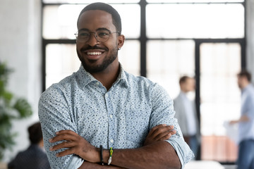 Happy motivated African American businessman in glasses look away thinking or pondering, smiling biracial male employee lost in thoughts consider career opportunities, business vision concept - obrazy, fototapety, plakaty