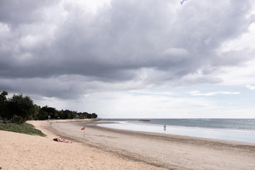 Fototapeta na wymiar Deserted beach on the island of Bali. Clouds and clouds with rain of dark blue color. Sandy beach with sea and ocean. Tropical view. Hurricane.