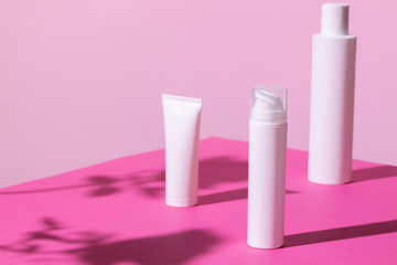 Skincare products containers on bright pink background close up