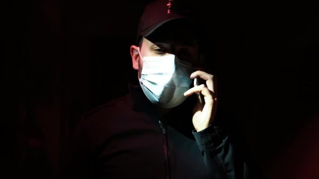 Young Man With A Mask Answering A Phone Call Under Flashing Light