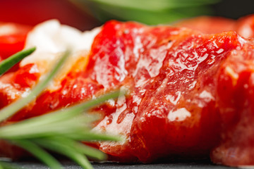 Raw beef kebab with herbs on a dark board, close up