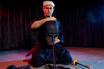 caucasian kendo fighter sit on the floor before fighting, wearing special kendo dress and using all...