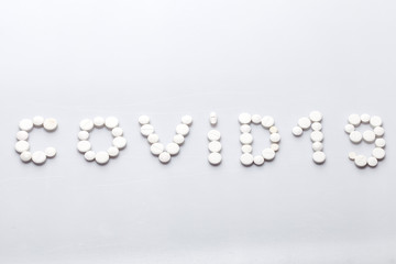 Covid-19 inscription made of round white tablets on a white background, medical concept on the theme of the coronavirus pandemic with copy spce.