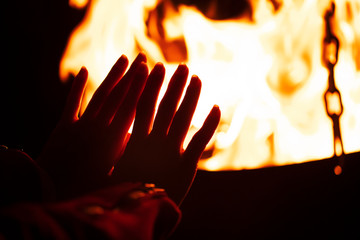 woman warming her hands by the campfire