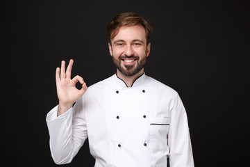 Smiling handsome young bearded male chef cook or baker man in white uniform shirt posing isolated...