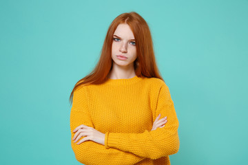 Displeased young redhead woman girl in yellow sweater posing isolated on blue turquoise wall...