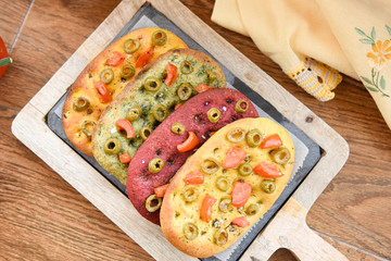 variety of different focaccia, with pumpkin, carrot and beet, on a rustic table