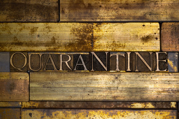 Photo of real authentic typeset letters forming Quarantine text on vintage textured grunge copper background