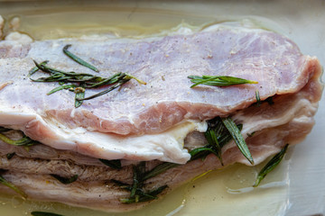Raw fat pork meat seasoned with salt, papper, garlic and rosemary branches