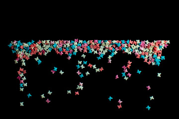 multicolored confectionery sprinkle in the form of butterflies on a black background