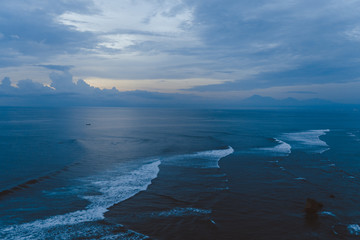 Beautiful blue sunset on the ocean with big waves and cliffs and cliffs. Bali island with its tropical and exotic nature. Sunrise over the sea and ocean. Phantom blue in sunset