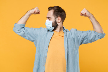 Strong young man in sterile face mask posing isolated on yellow background studio portrait....