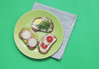  Sandwiches with healthy vegetables, tomatoes, eggs, micro greens on plate on colorful background. Healthy food concept.
