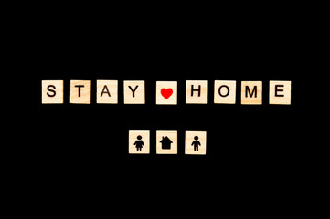Wooden blocks with letters on black background. Stay home concept. Stop coronavirus concept. Social distancing. People at home. Family at home. Images of man and women