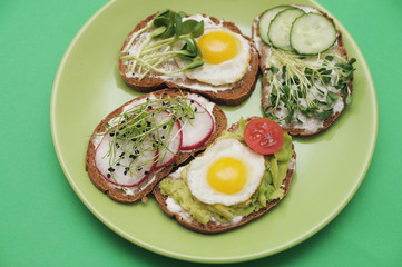  Sandwiches with healthy vegetables, tomatoes, eggs, micro greens on plate on colorful background....
