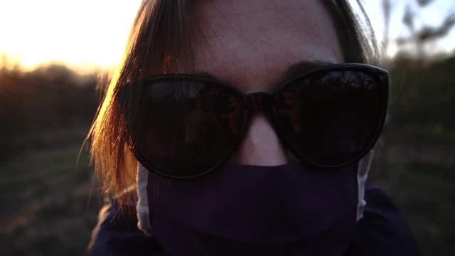 girl alone without people in a protective mask from coronavirus in sunglasses at sunset