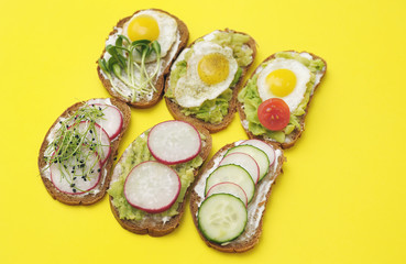  Sandwiches with healthy vegetables, tomatoes, eggs, micro greens on yellow background.