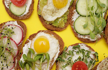  Sandwiches with healthy vegetables, tomatoes, eggs, micro greens on plate on colorful background. Healthy food concept.